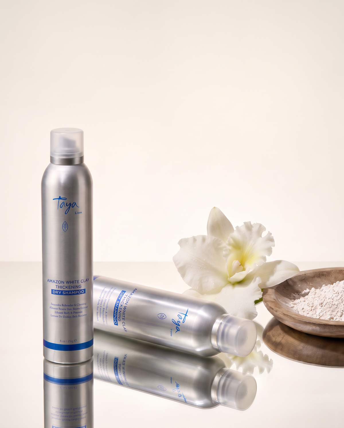 TAYA Amazon White Clay Thickening Dry Shampoo on a mirrored ivory surface with a white orchid and white clay